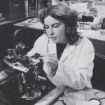 Black and white photo of a woman in a lab coat in a lab